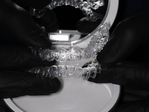 Gloved hands holding upper and lower clear aligner trays at Y3 Smiles Dental