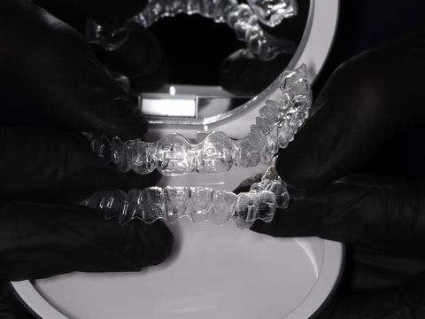 Gloved hands holding upper and lower clear aligner trays at Y3 Smiles Dental