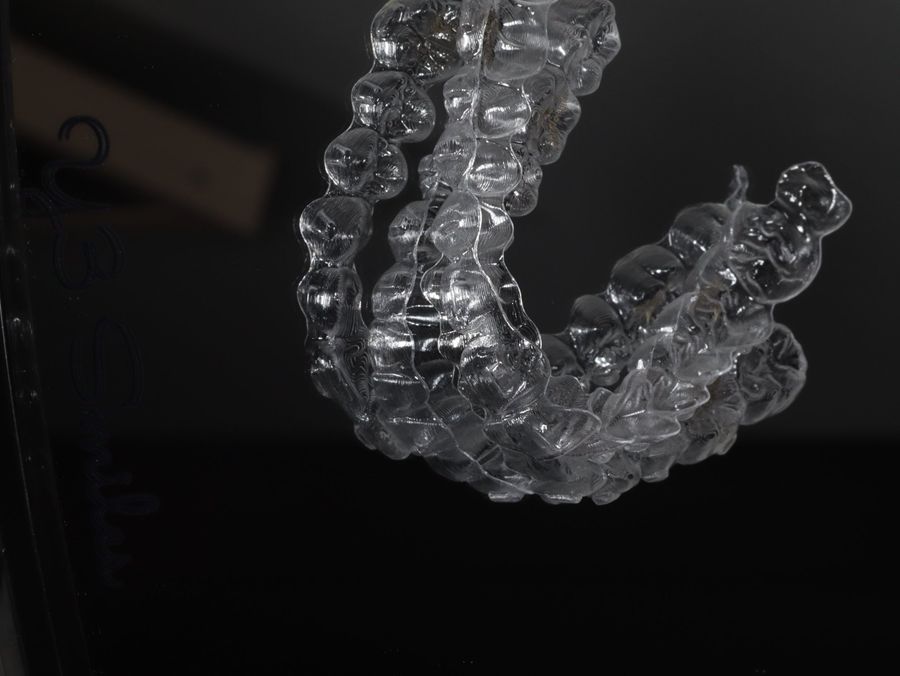 A set of clear aligner trays beside the Y3 Smiles logo