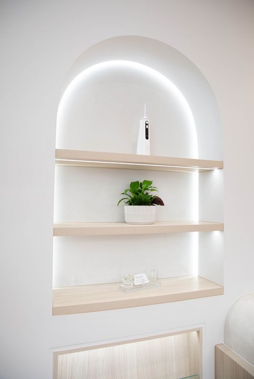 Arched, backlit shelving with plants in the Y3 Smiles Dental reception area
