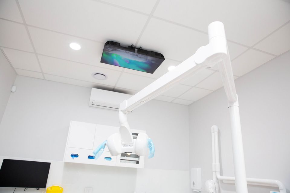 Treatment room with a ceiling-mounted screen at Y3 Smiles Dental