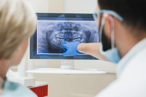 Dentist reviewing a dental x-ray on screen with a patient